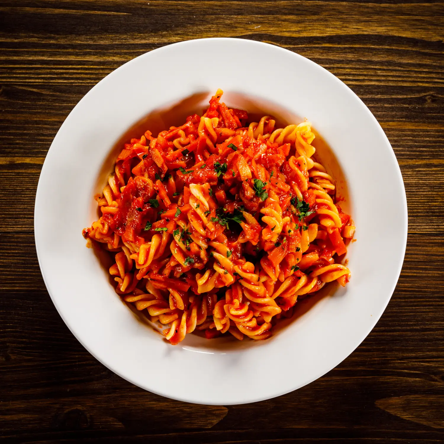 Nudeln mit Tomatensauce und Gemüse auf Holztisch